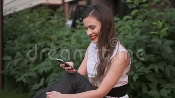 无忧无虑的商务女性赤脚坐在公园的长椅上用手机发短信视频的预览图