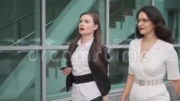 商业女性走在现代商业建筑旁边两个有吸引力的女人正在谈论视频的预览图