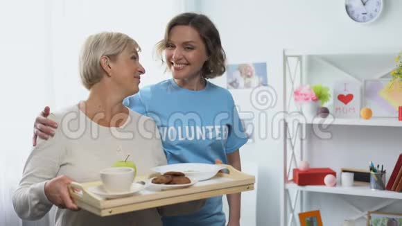 社工抱着拿着餐盘的退休妇女义工来访视频的预览图