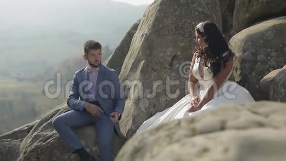 新郎和新娘坐在山上的高坡上新婚夫妇快乐视频的预览图