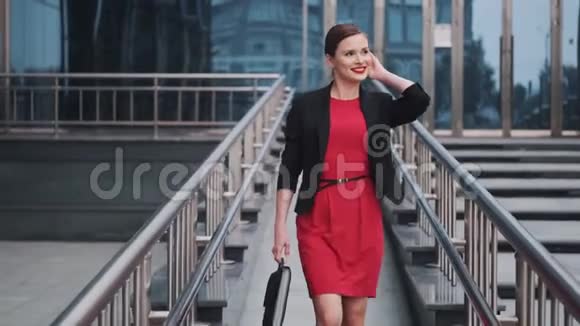 一位年轻女子的画像她穿着夹克手里拿着公文包自信的红衣女商人视频的预览图