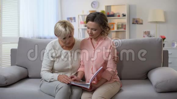 悲伤的成年女性和母亲一起翻阅家庭相册回忆视频的预览图