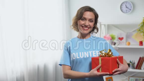 女志愿者手拿礼盒对着镜头微笑捐款慈善视频的预览图