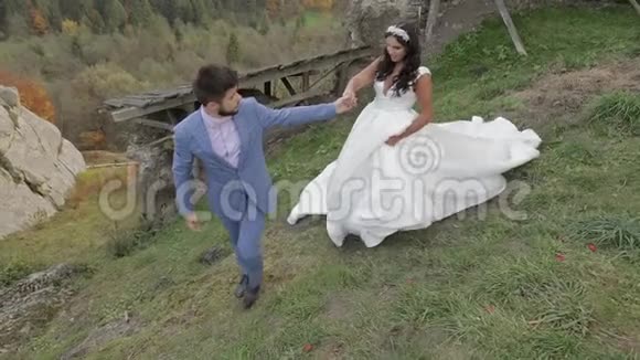 新郎和新娘在森林里的山上散步新婚夫妇视频的预览图