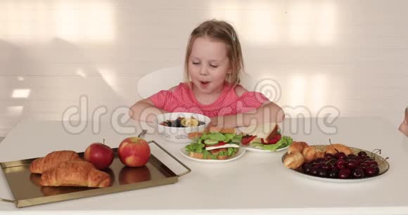 可爱的孩子们在吃早餐两个姐妹在早餐桌上视频的预览图