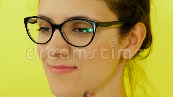 戴着耳机和眼镜的黄色背景上的女孩的肖像视频的预览图
