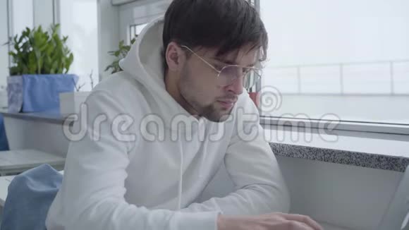 帅哥坐在咖啡馆里等待他的命令或在中心专心地在电脑上工作的肖像视频的预览图