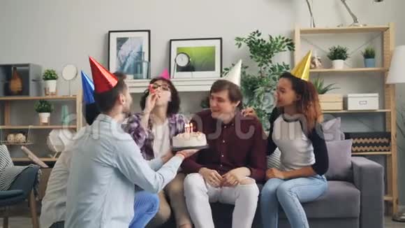 男人在生日蛋糕上吹蜡烛朋友在家里祝贺拥抱视频的预览图