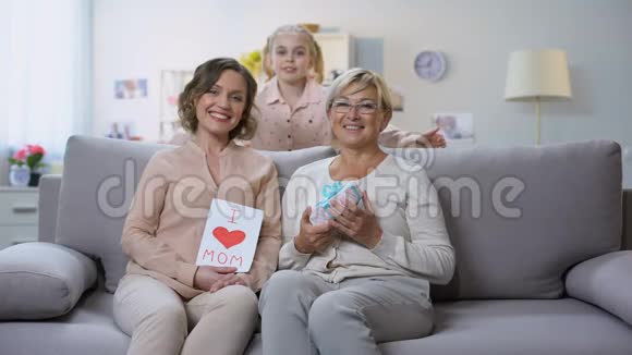 可爱的女孩用礼物盒和手工贺卡拥抱妈妈和奶奶视频的预览图