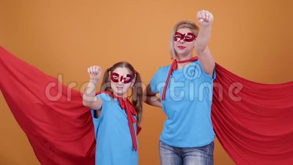 一个年轻女孩和一个女人在橙色背景下当超级英雄视频的预览图