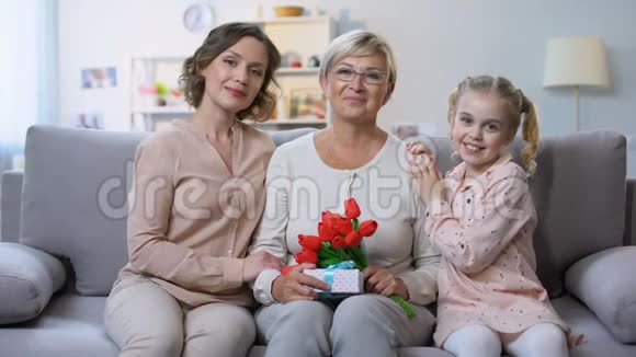 母亲和女儿用郁金香拥抱祖母手里拿着礼物度假视频的预览图