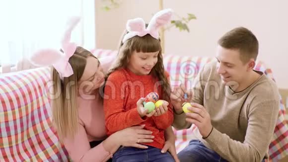 白人家庭由父亲母亲和孩子组成坐在沙发上准备复活节油漆视频的预览图