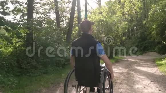 一个坐在轮椅上的残疾青年男子慢镜头跟随他观察周围的自然太阳耀斑视频的预览图