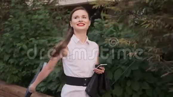 快乐的女人正沿着街走快乐的商人手里拿着公文包视频的预览图