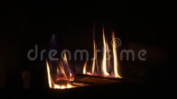 在舒适的砖制壁炉中用橙色火焰缓慢燃烧的木头上拍摄了令人满意的特写镜头视频的预览图