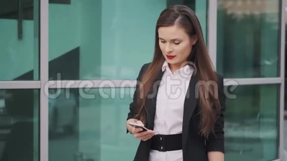 年轻的商务女性浏览智能手机上的信息自信地走在街上视频的预览图
