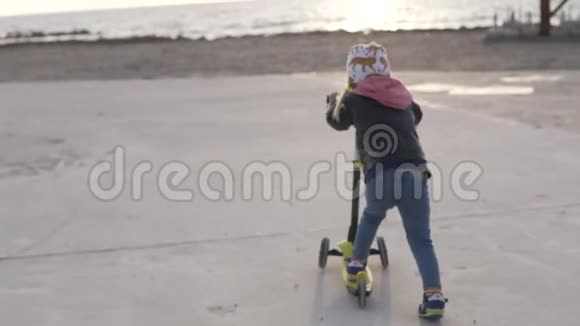 时髦的小女孩在海滩上骑滑板车视频的预览图