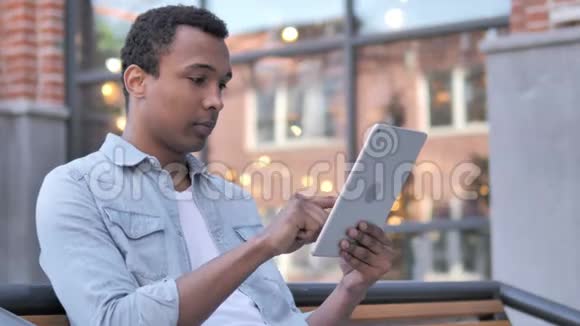 坐在户外的非洲男人在平板电脑上欢呼成功视频的预览图