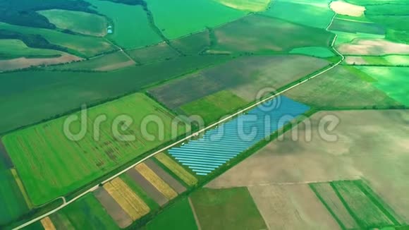 空中无人机俯瞰绿色田野中的大型太阳能农场变焦4公里视频的预览图