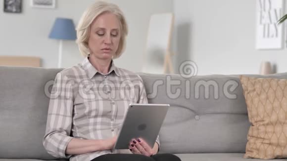 女士在沙发上休息时使用平板电脑视频的预览图