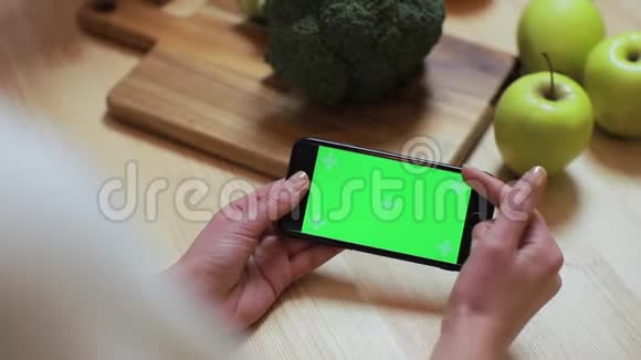 在家厨房里用chroma键特写女人的手浏览智能手机早餐浏览商务食品女孩视频的预览图