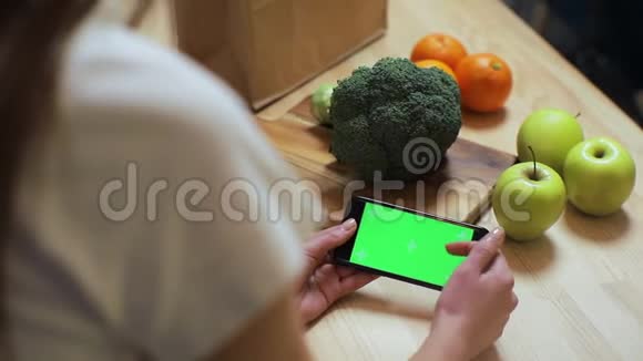 在家厨房里用chroma键特写女人的手浏览智能手机早餐浏览商务食品女孩视频的预览图