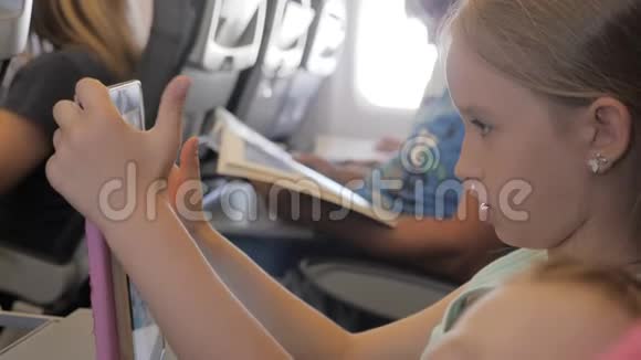 可爱的女孩乘飞机旅行在飞行中使用数字平板电脑与孩子一起出国旅行的概念视频的预览图
