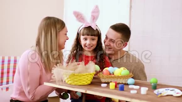 快乐的父母和她的女儿在镜头中展示他们的作品即一个明亮而多彩的复活节彩蛋视频的预览图