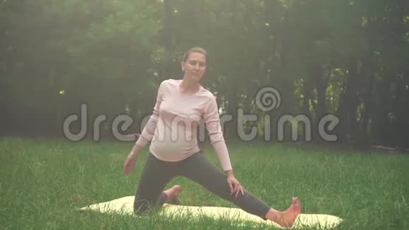 孕妇在公园里做瑜伽的地毯上单腿站在膝盖上的姿势螺栓视频的预览图