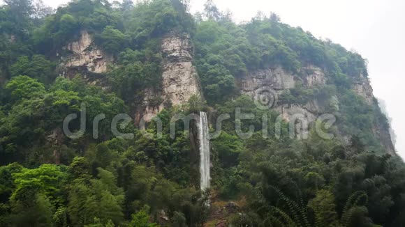 美丽的瀑布从山上的岩石中倾泻而出茂密的常青森林视频的预览图
