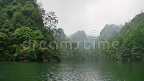 雾中覆盖热带森林的张家界山脉的河流景观视频的预览图