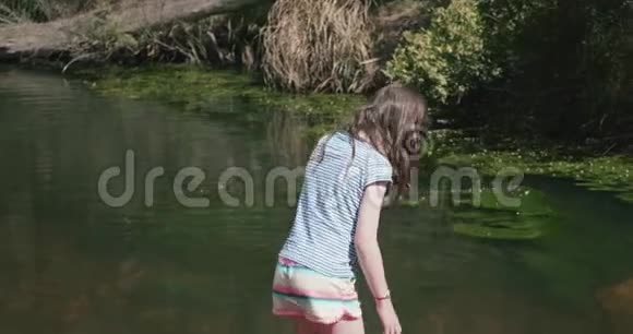 小女孩走上河中的一块岩石然后弯下腰泼水视频的预览图