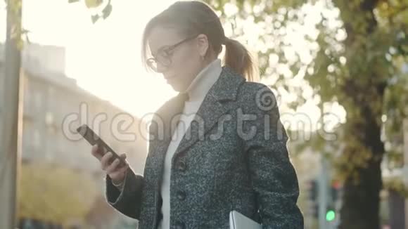 在户外打电话的女人戴眼镜和外套的女孩的肖像视频的预览图