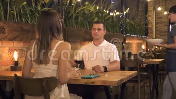 浪漫的情侣在晚间餐厅用餐女服务员招待年轻夫妇而约会在优雅的咖啡馆浪漫晚餐视频的预览图