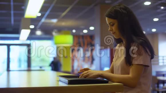 吃汉堡的年轻女士坐在咖啡馆的桌子上垃圾食品成瘾不健康的膳食视频的预览图