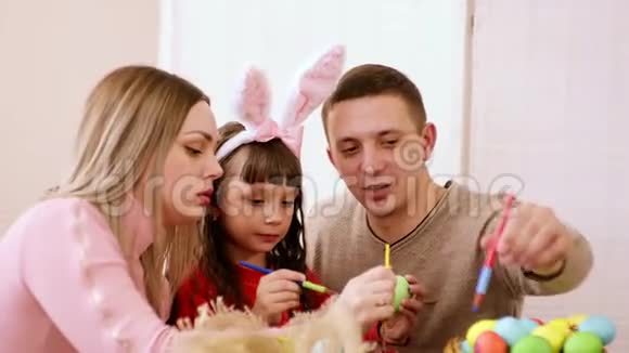 幸福的家庭一起为复活节准备一些餐桌上的乐趣女孩拿着一个鸡蛋而她的父母在帮助下视频的预览图
