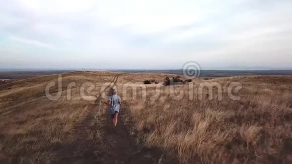 女人在乡间的道路上奔跑穿过干旱的土地和山丘视频的预览图