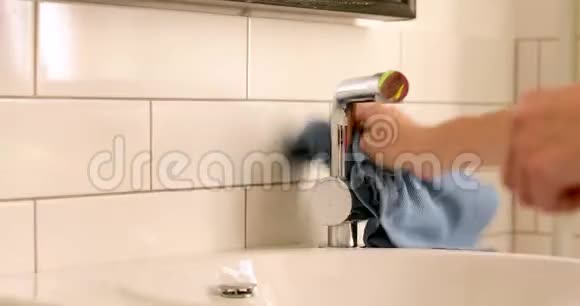 用毛巾擦拭水龙头的人视频的预览图