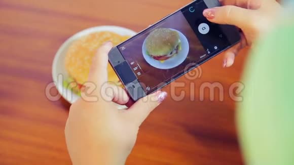 女性手拿着手机给汉堡拍照视频的预览图