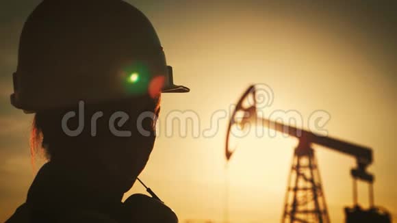 剪影女工程师戴白色头盔日落时穿工作服工业石油和天然气的概念视频的预览图