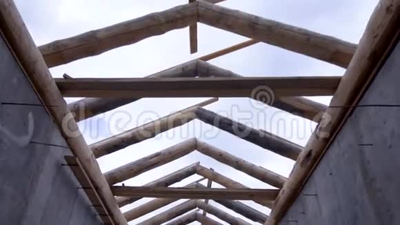 底部看木桁架系统在多云的天空背景下建造房屋屋顶剪辑未完成的屋顶和两个视频的预览图