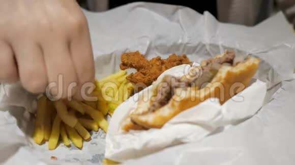 女人吃薯条鸡肉和汉堡在快餐店食品特写视频的预览图