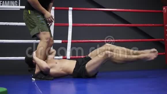 男高拳手与教练一起训练一个运动员躺在拳击场的地板上用视频的预览图