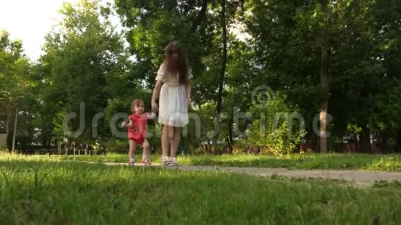 妈妈和小女儿正在夏日公园的小路上散步宝宝和妈妈的第一步视频的预览图