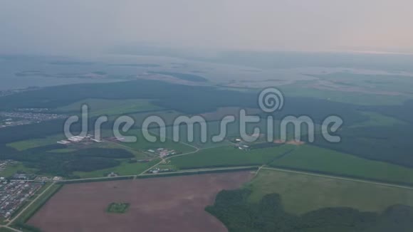 从飞机窗口在薄雾中俯瞰沿海城镇田野和海洋视频的预览图