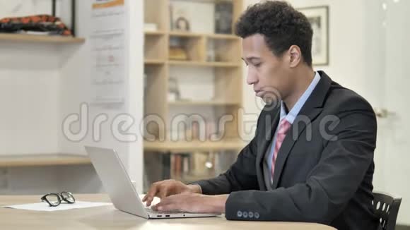 疲劳的非洲商人颈部疼痛的笔记本电脑视频的预览图