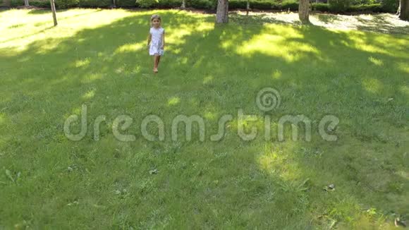 四岁的小快乐女孩正在公园的绿草上奔跑视频的预览图