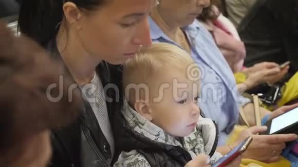 年轻的母亲和小儿子在乘地铁旅行时使用电话视频的预览图