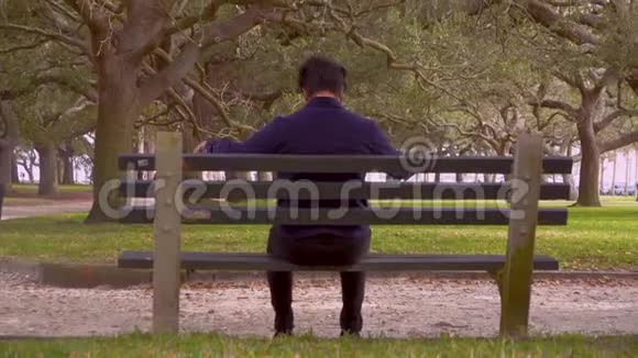 坐在公共公园的长椅上假装弹钢琴的人视频的预览图