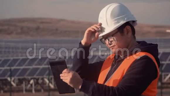亚洲外观工程师正在仔细研究平板电脑上的工作报告并调整他头上的头盔视频的预览图